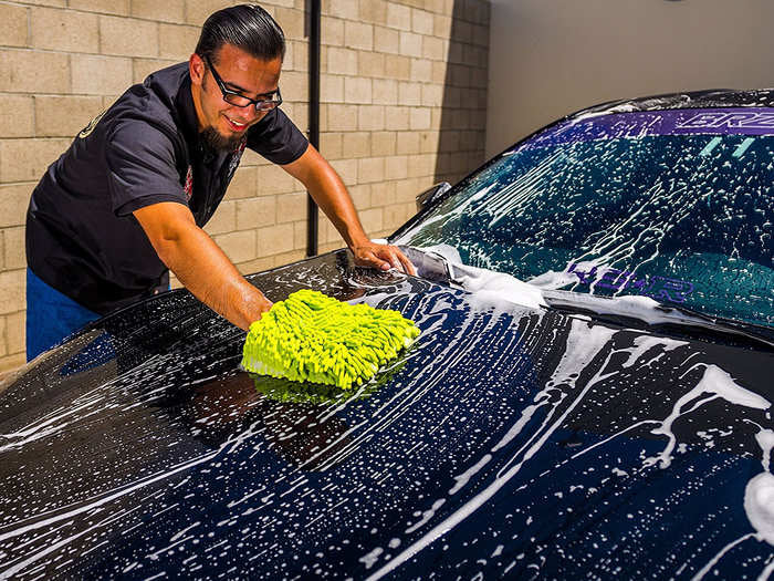 Person washing car with water and soap in carwash. Man with high